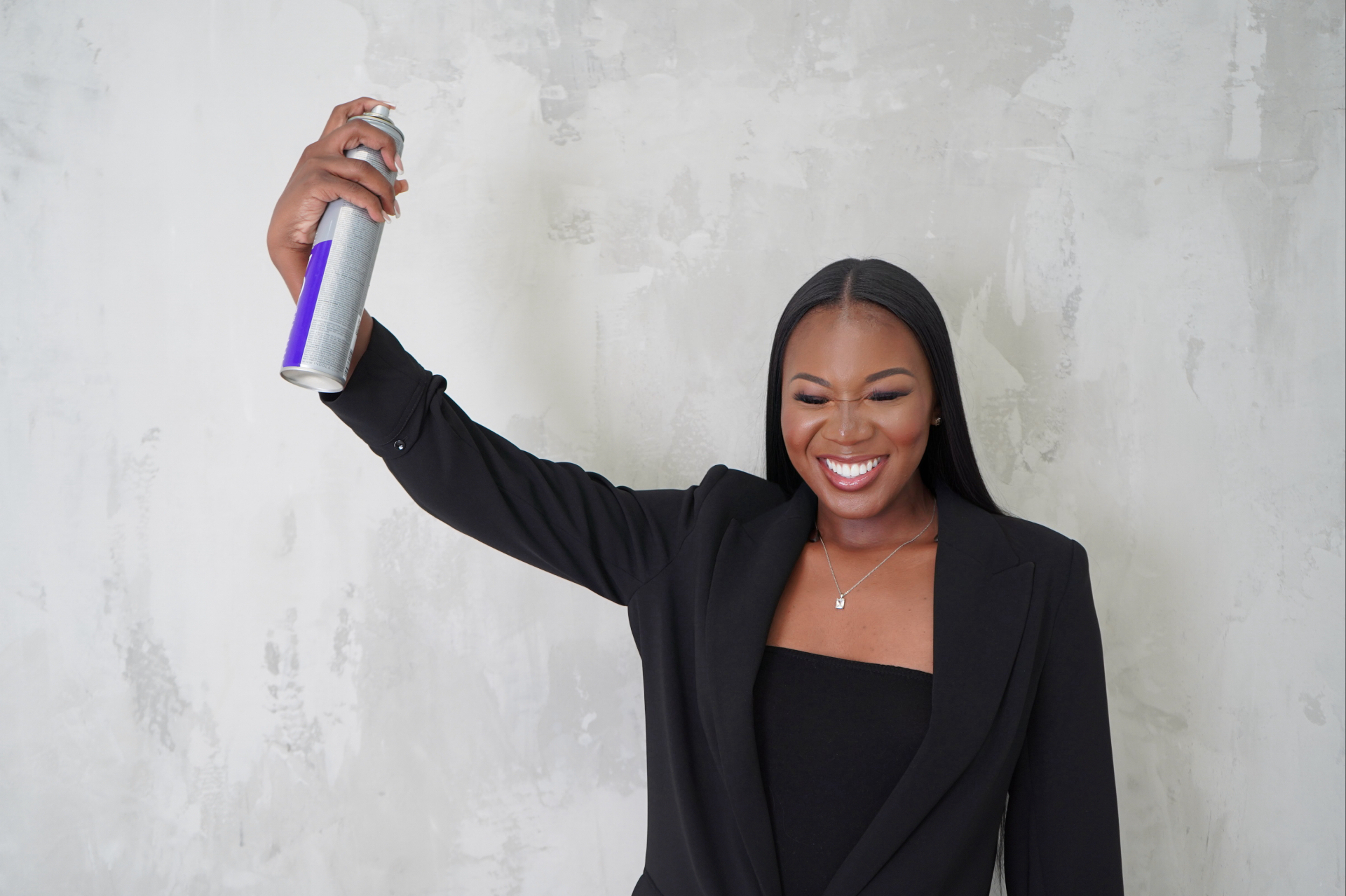 Meredith Shola laughing while spraying hairspray